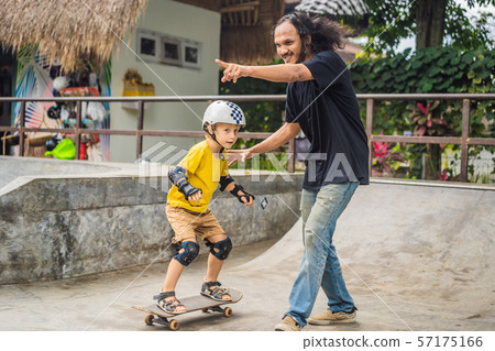 Athletic boy learns to skateboard with a trainer in a skate park. Children education, sports 57175166