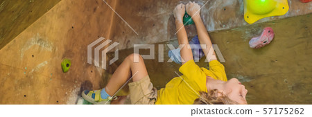 little boy climbing a rock wall in special boots. indoor BANNER, LONG FORMAT 57175262