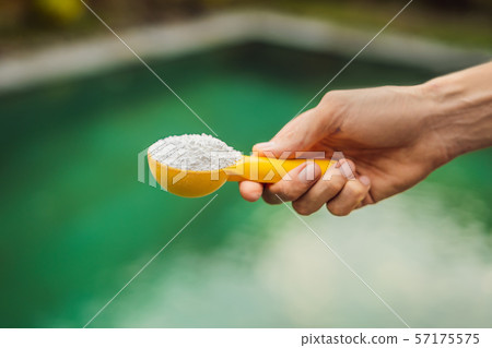Hand holding Chlorinefor water in the pool 57175575