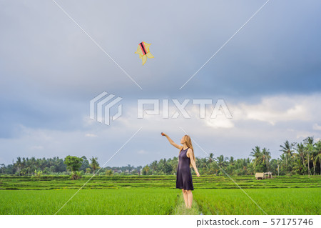 Young woman tourist launches a kite in a rice field in Ubud, Bali Island, Indonesia Young woman tourist launches a kite in a rice field in Ubud, Bali Island, Indonesia 57175746