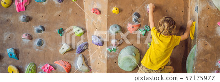 little boy climbing a rock wall in special boots. indoor BANNER, LONG FORMAT 57175977