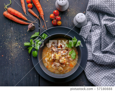 Delicious pea soup with chicken meat and vegetables. Dark plate on a dark wooden background. Top 57180888