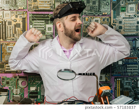 Young male electrician engineer tiredly yawns Young male electrician engineer tiredly yawns 57183837