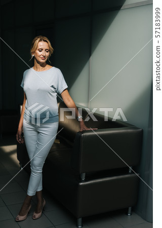 Attractive blonde posing standing by the black couch 57183999