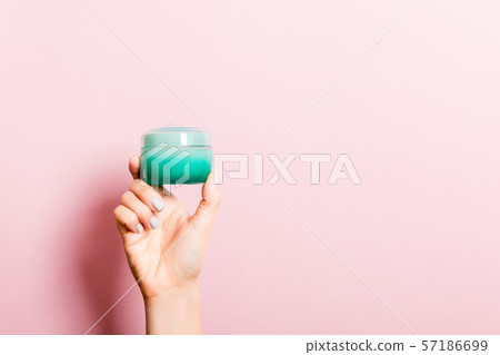 Female hand holding cream bottle of lotion 57186699