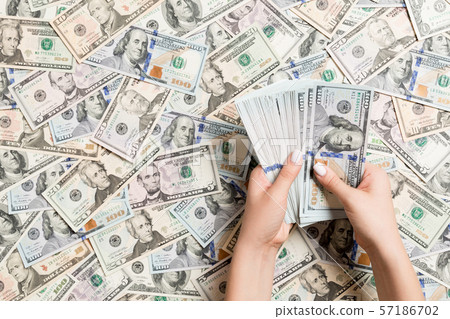 Top view of female hands counting money on dollar Top view of female hands counting money on dollar 57186702