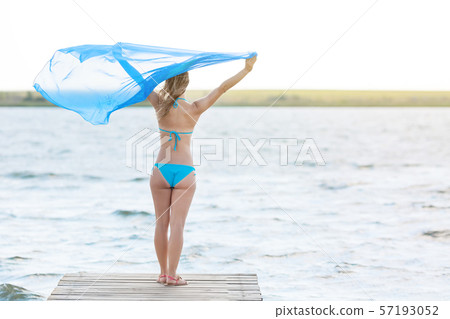 Slender girl with a big scarf on the shore. Slender girl with a big scarf on the shore. 57193052