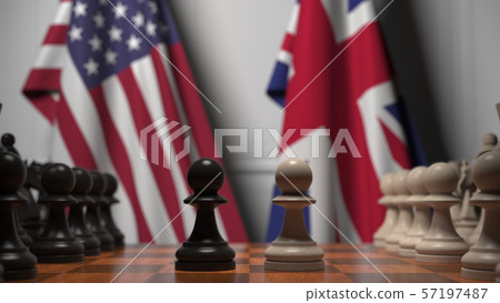 Flags of United States and United Kingdom behind chess board. The first pawn moves in the beginning 57197487
