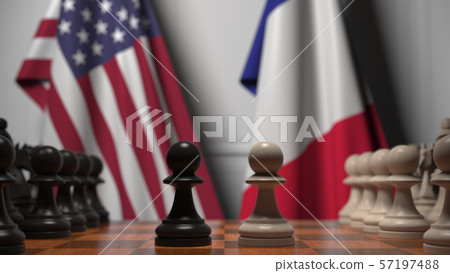 Flags of United States and France behind chess board. The first pawn moves in the beginning of the 57197488