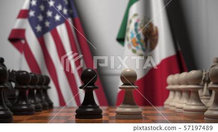 Flags of United States and Mexico behind chess board. The first pawn moves in the beginning of the 57197489