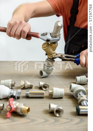 A worker is connecting elements of the plumbing. 57197768