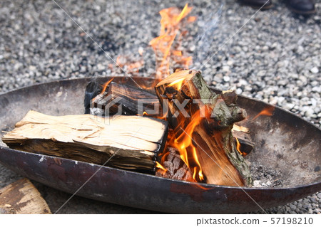 Burning wood of campfire in metal fire bowl on a pebble floor Burning wood of campfire in metal fire bowl on a pebble floor 57198210