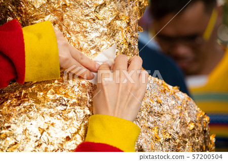 Close-up of woman hand making merit. Gilding gold 57200504