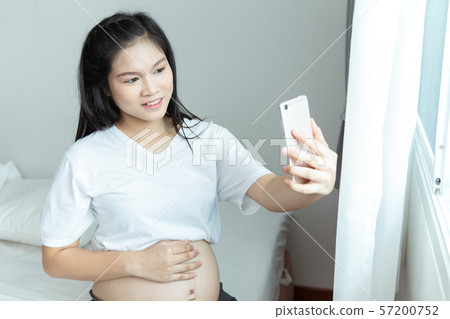 Cheerful pregnant young Asians woman sitting on Cheerful pregnant young Asians woman sitting on 57200752