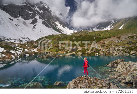 Hiking woman in red jacket stay at beautiful lake in mountains. 57201155