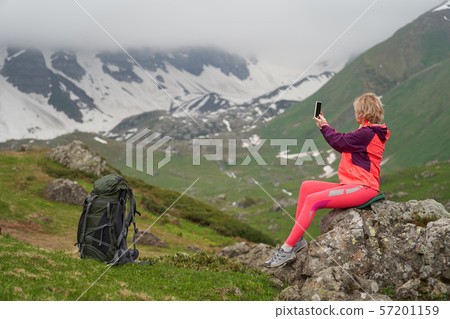 Portrait of woman taking a picture at the beautiful mountains background. 57201159