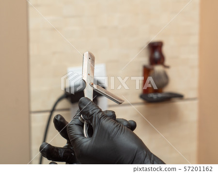Stylist preparing open razor for shaving, close up 57201162