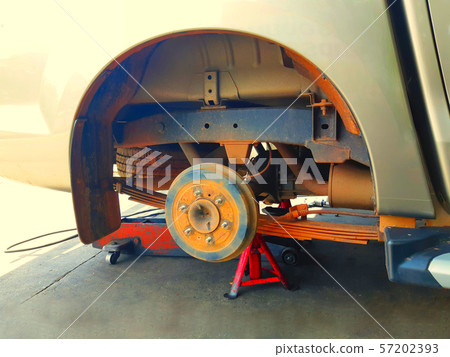 Closeup of front wheel of a car without a tire together with impact wrench and bolts laying on the ground during tire replacement at a mobile maintenance workshop 57202393