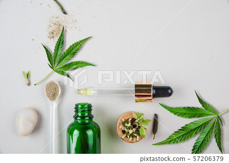 Glass green bottle and pipette with CBD oil and cannabis leaf on background 57206379
