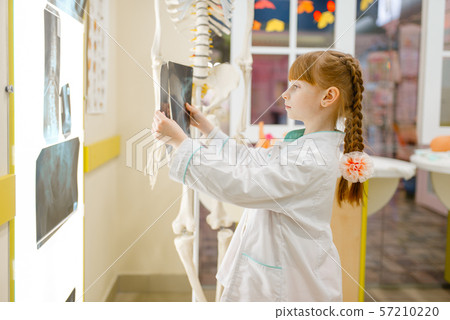 Little girl in uniform looks at the x-ray, doctor 57210220