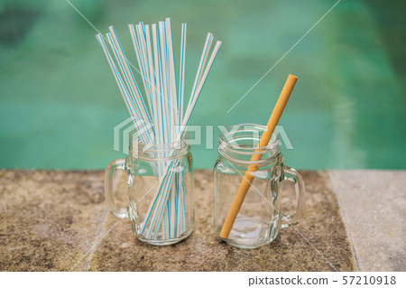 Bamboo drinking straw vs disposable straws on the background of the pool. Zero waste concept 57210918