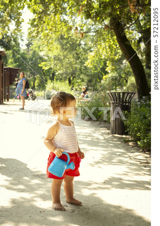 Cute kid with watering can in a playground Cute kid with watering can in a playground 57212095