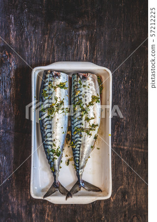 two raw fish mackerel in greens and herbs will be baked on a dark background. View from above. Retro 57212225