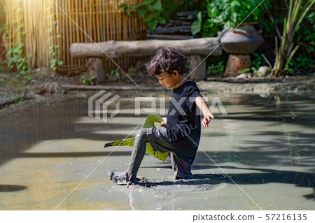 Asian boy playing with mud in a fun place inside a Asian boy playing with mud in a fun place inside a 57216135