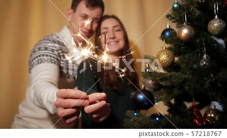 happy couple in sweaters hold bright sparklers near camera happy couple in sweaters hold bright sparklers near camera 57218767