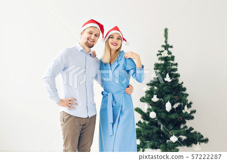 Winter holidays and family concept - Happy young couple near Christmas tree at home Winter holidays and family concept - Happy young couple near Christmas tree at home 57222287