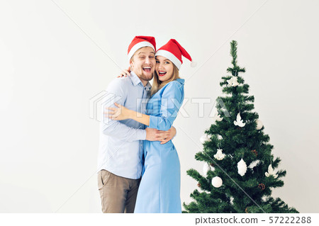 Winter holidays and family concept - Happy young couple near Christmas tree at home Winter holidays and family concept - Happy young couple near Christmas tree at home 57222288