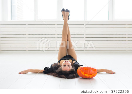 Halloween and masquerade concept - Beautiful young woman posing with Pumpkin Jack-o'-lantern Halloween and masquerade concept - Beautiful young woman posing with Pumpkin Jack-o'-lantern 57222296