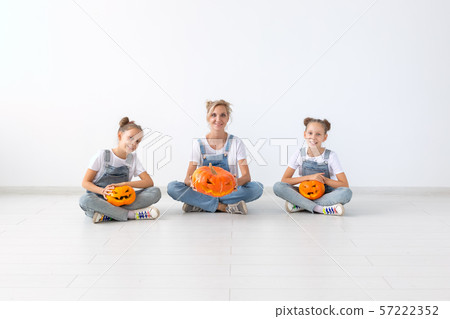 Happy halloween and holidays concept - A mother and her daughters with pumpkins. Happy family 57222352
