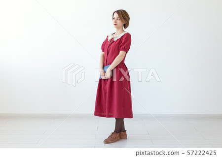 Portrait of cute smiling modest woman in dress holding classic book in hands on white background Portrait of cute smiling modest woman in dress holding classic book in hands on white background 57222425