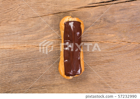 Dessert eclair with chocolate cream on wooden background. Dessert eclair with chocolate cream on wooden background. 57232990