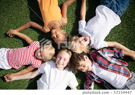 Children making funny faces while chilling on grass Children making funny faces while chilling on grass 57234447