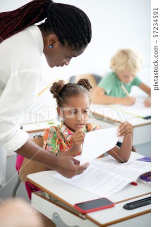 Dark-eyed girl correcting her mistakes after writing test Dark-eyed girl correcting her mistakes after writing test 57234591