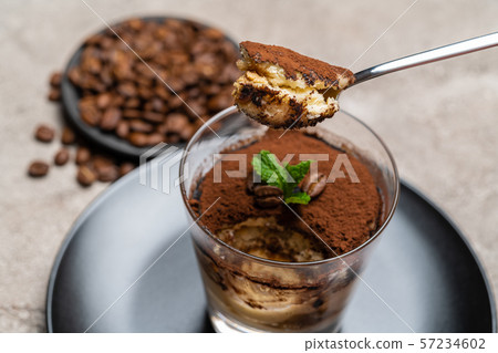 Portion of Classic tiramisu dessert in a glass cup on concrete background Portion of Classic tiramisu dessert in a glass cup on concrete background 57234602
