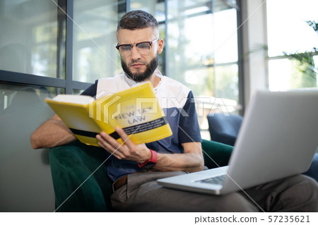 Bearded businessman wearing glasses reading tax book Bearded businessman wearing glasses reading tax book 57235621