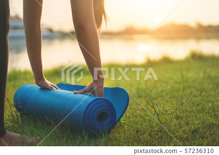Young asian woman rolling blue yoga mat or fitness Young asian woman rolling blue yoga mat or fitness 57236310