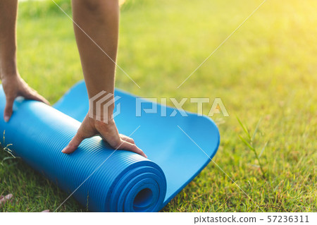 Young asian woman rolling blue yoga mat or fitness Young asian woman rolling blue yoga mat or fitness 57236311