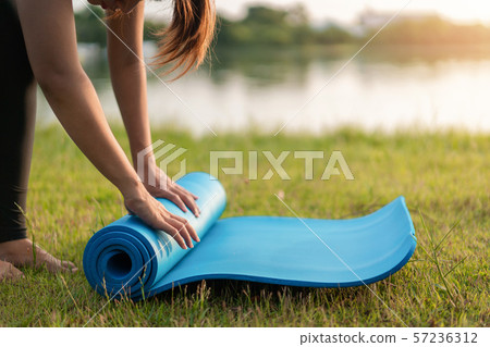 Young asian woman rolling blue yoga mat or fitness Young asian woman rolling blue yoga mat or fitness 57236312