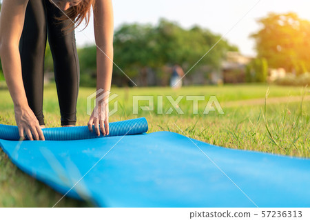 Young asian woman rolling blue yoga mat or fitness Young asian woman rolling blue yoga mat or fitness 57236313