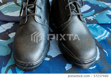 A pair of black army boots on fabric with blue 57237480