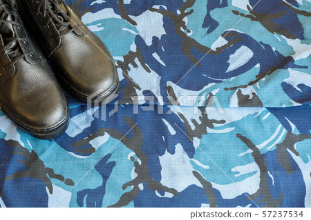 A pair of black army boots on fabric with blue A pair of black army boots on fabric with blue 57237534