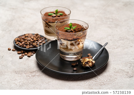 Portion of Classic tiramisu dessert in a glass cup on concrete background Portion of Classic tiramisu dessert in a glass cup on concrete background 57238139