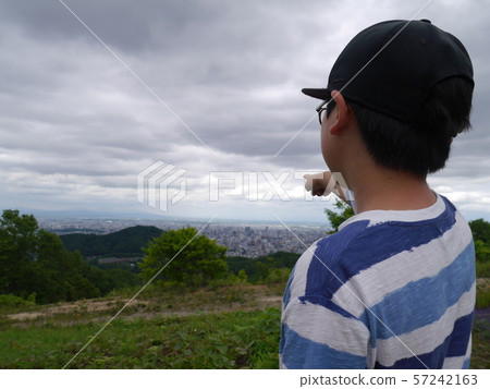 A boy looking at the cityscape of Sapporo from the Horomi Pass 57242163
