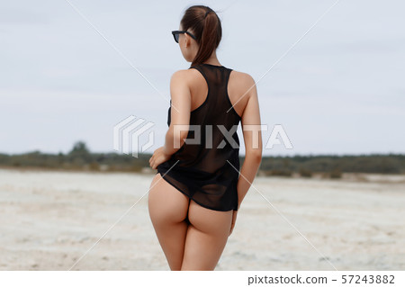 Sensual slim female in black swimsuit on beach Sensual slim female in black swimsuit on beach 57243882