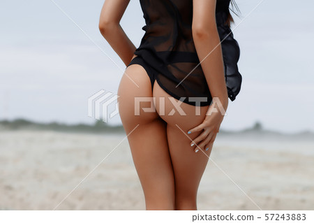 Sensual slim female in black swimsuit on beach Sensual slim female in black swimsuit on beach 57243883