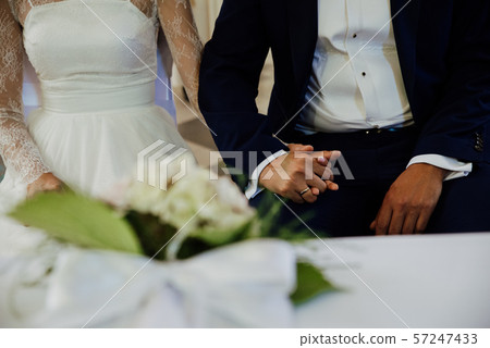 the young couple holds hands during the wedding 57247433
